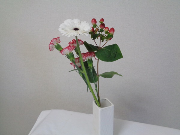 白色のガーベラ、白色と赤色のカーネーション、赤色の実の植物